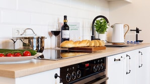 A kitchen with a stainless steel pot, a loaf of bread, a bottle of wine, and a coffee maker. - Apartment 'Fewo Saalstube, Adolphsburg' with Shared Garden and Wi-Fi (Kirchhundem)