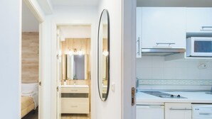 Habitación de hotel con cama, baño con espejo, lavamanos y microondas.