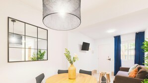 Un comedor moderno con una mesa redonda, sillas, un espejo grande, una lámpara colgante y una planta en maceta.