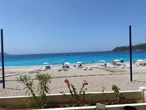 A beach with sun loungers and umbrellas, a clear blue sea, and a distant shoreline. - Large four bedroom Villa in Beautiful quiet location, private pool and barbecue (Oludeniz)