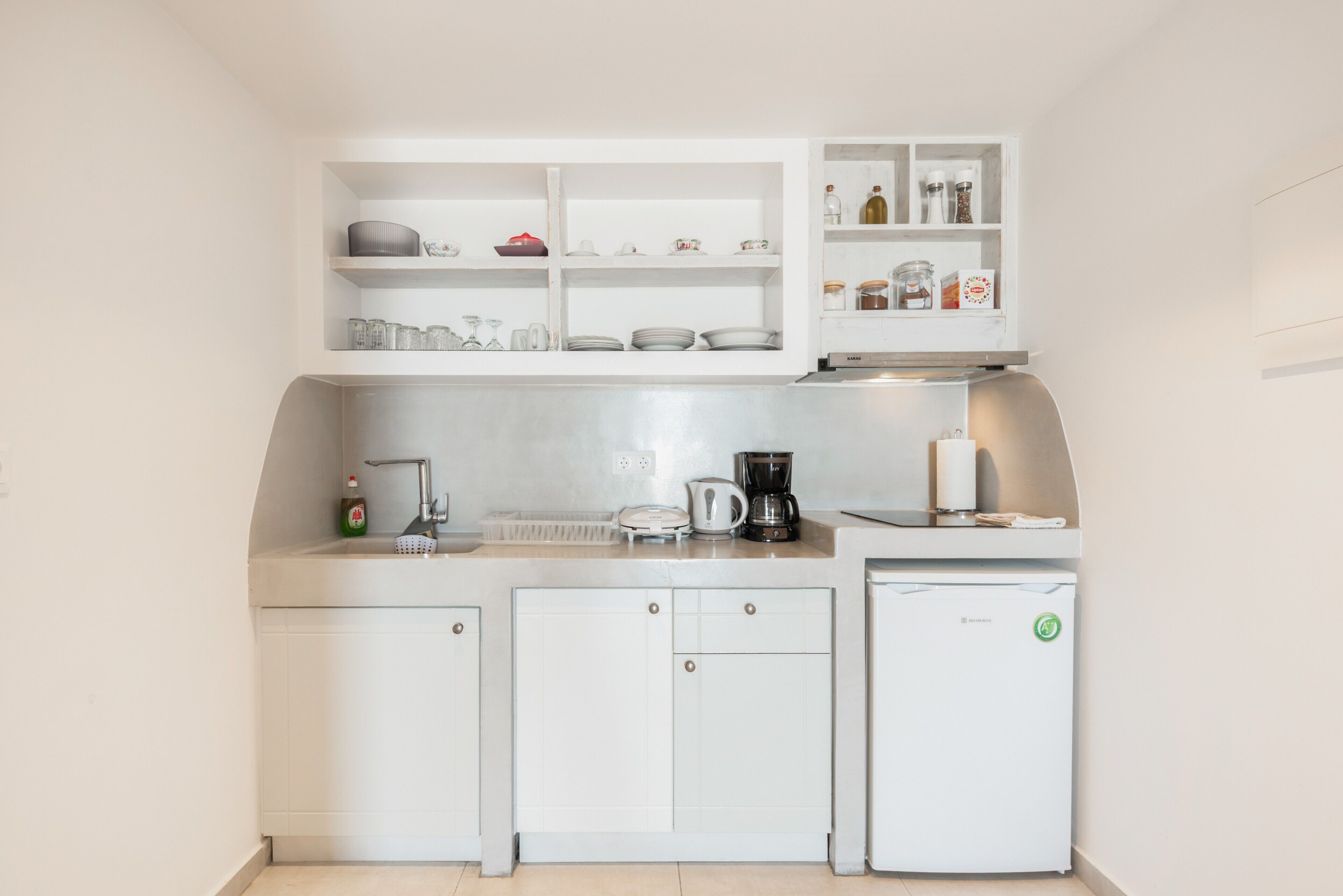 A compact kitchen with white cabinets, a coffee maker, and a dishwasher.