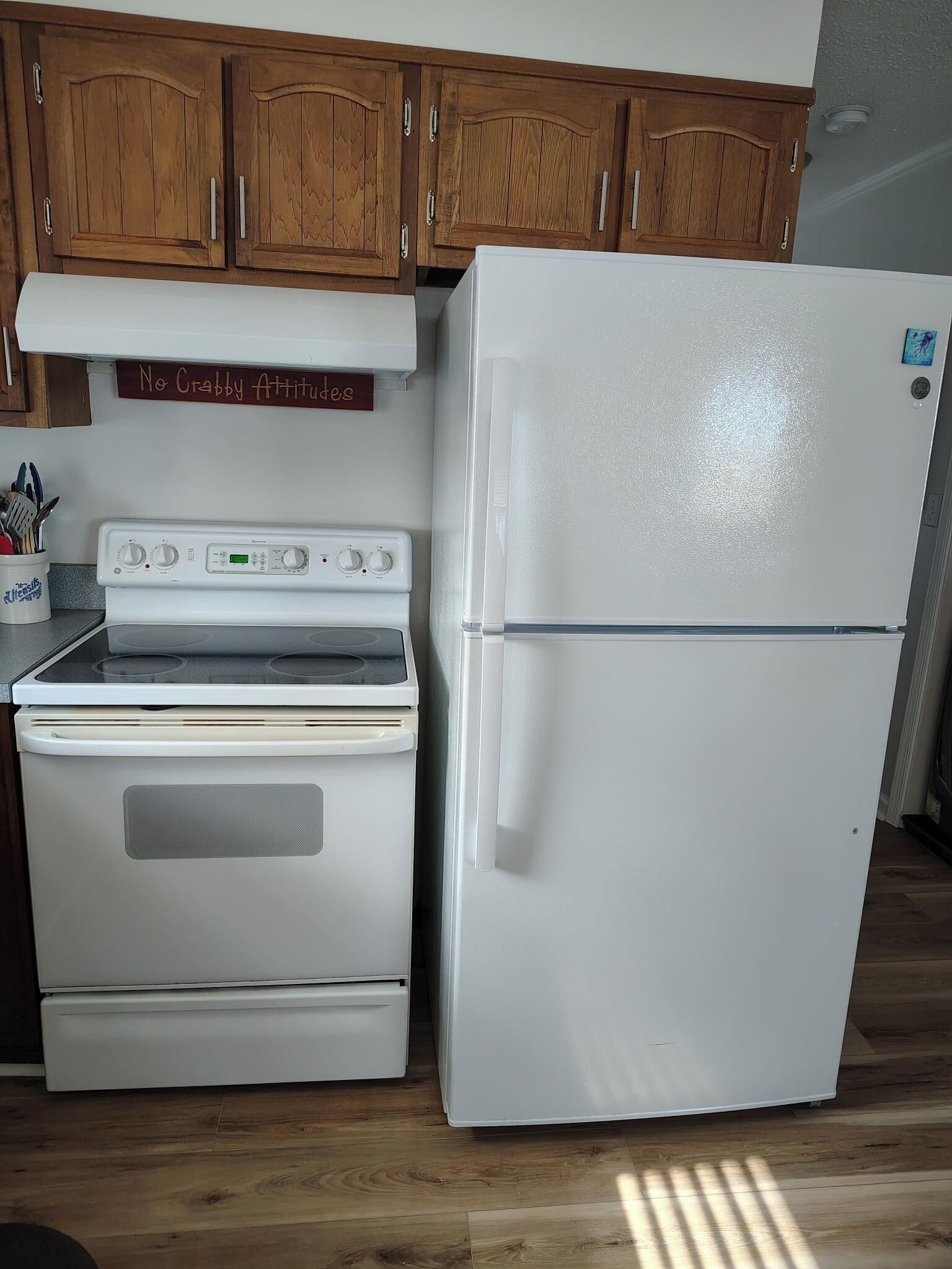 A kitchen with wooden cabinets, a white stove, and a white refrigerator.