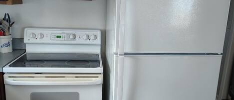 A kitchen with wooden cabinets, a white stove, and a white refrigerator.