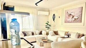 Een woonkamer met een zithoek, een salontafel, een waterfles en een potplant.