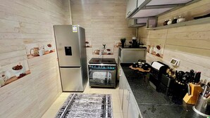 Een praktische keuken met een koelkast, oven, koffiezetapparaat en messenblok.