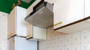 Una cocina con gabinetes blancos, horno de acero inoxidable, microondas y encimera de madera.
