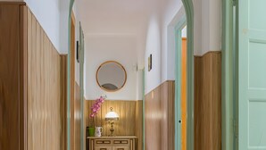 Un pasillo con paneles de madera, un espejo, una lámpara y un armario.