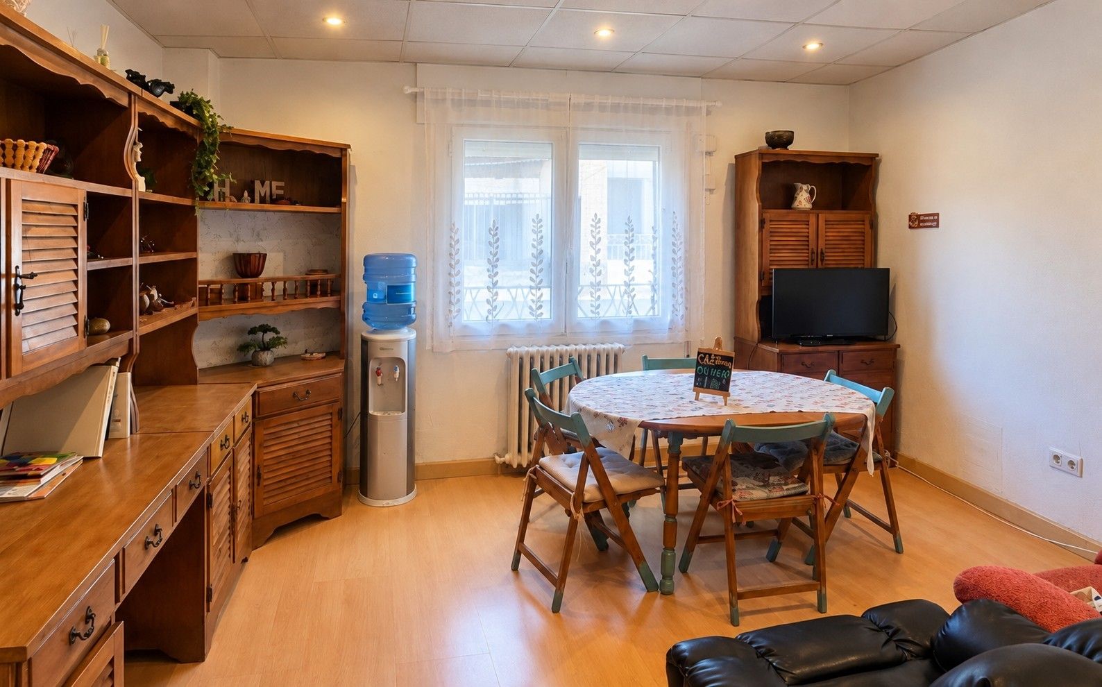 Una sala de estar acogedora con una mesa de centro de madera, un televisor y un dispensador de agua.