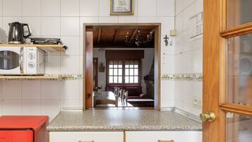 Una cocina con un microondas, un electrodoméstico rojo y una puerta de madera.