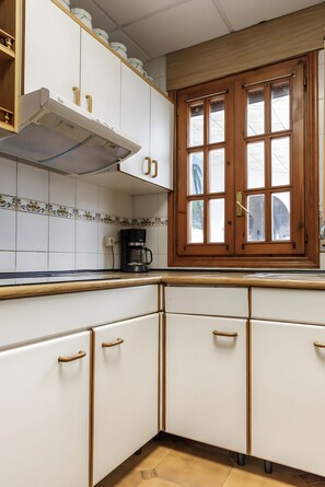 Una cocina con armarios blancos, una cafetera y una ventana con vistas.