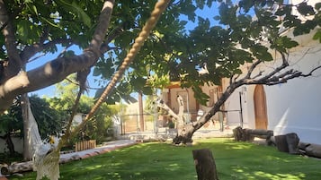 Un jardin bien entretenu, agrémenté d’un hamac, d’un banc en bois et d’un tronc d’arbre taillé en forme de souche.