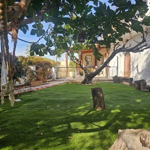Un jardín cuidado con césped, un tocón de árbol y un edificio al fondo.