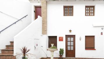 Un edificio blanco con una puerta roja, una ventana y un cartel que dice 'AT'.