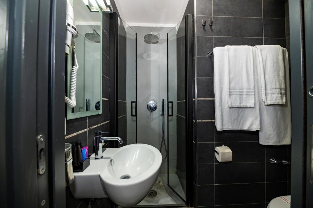 A modern bathroom with a sink, mirror, and shower.