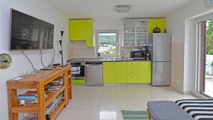 Eine kompakte Küche mit Fenster, ein Essbereich mit Tisch und Stühlen sowie eine kleine Sitzgelegenheit mit einer Bank.