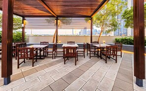 Eine Terrassengaststätte mit Tischen und Stühlen, ein Holz-Pergola und ein Blick auf den Stadtgürtel.