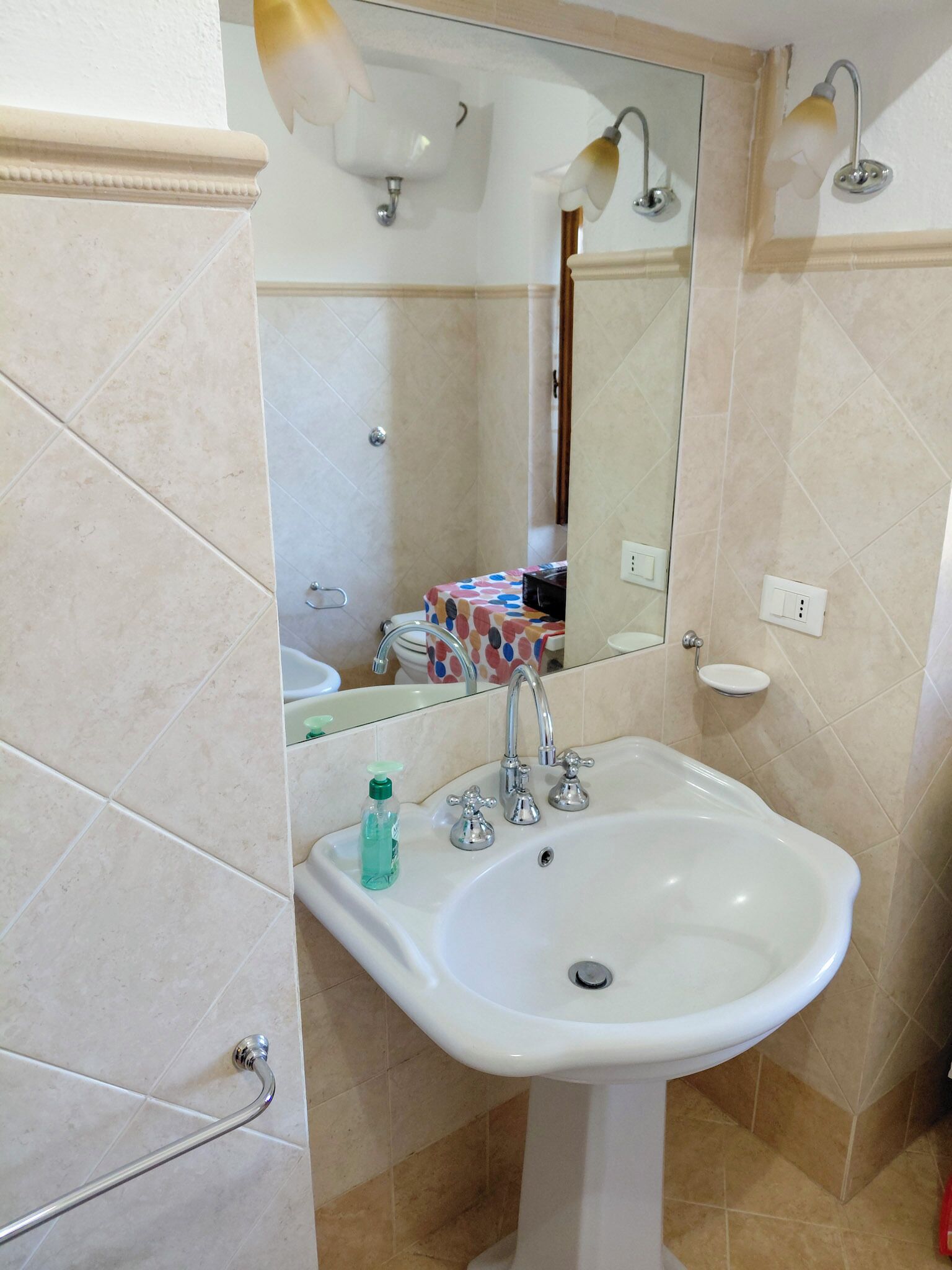Een badkamer met een witte wastafel, een spiegel en een douche.