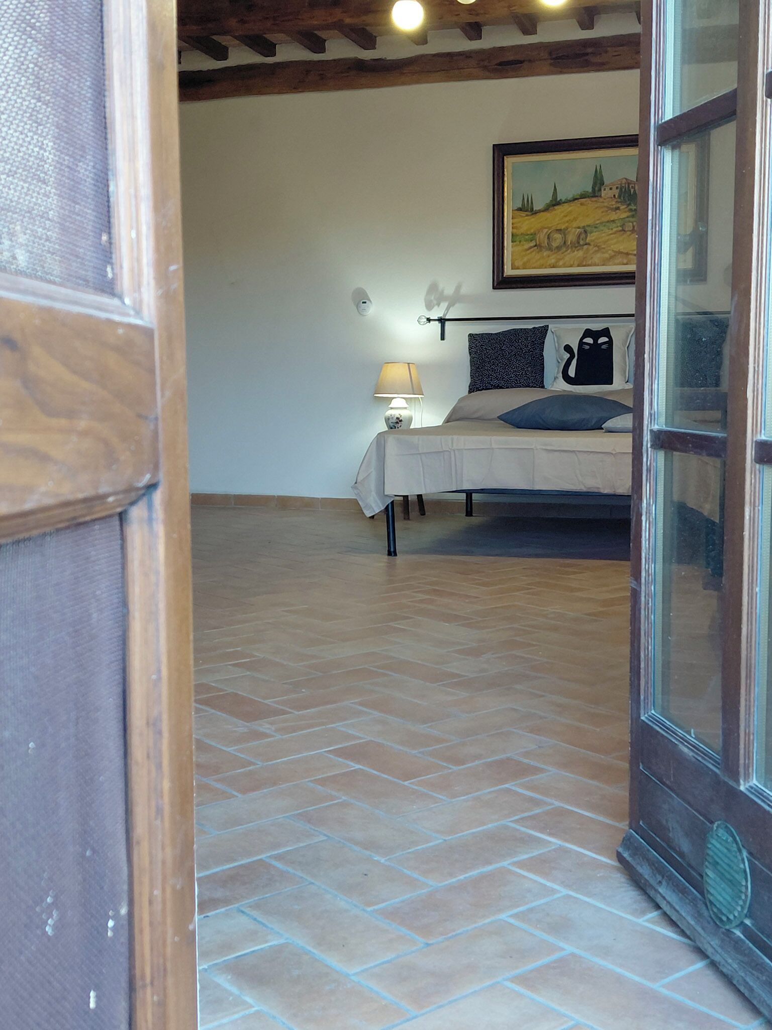 A bedroom with a bed, a nightstand, a lamp, and a painting on the wall.