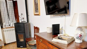 A cozy living room with a fireplace, a television mounted on the wall, a wooden cabinet, and a tiled floor. - La Dimora di Dida (Seggiano)