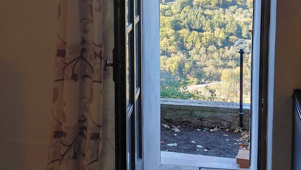 An open door leading to a balcony with a view of a forested hillside. - La Dimora di Dida (Seggiano)