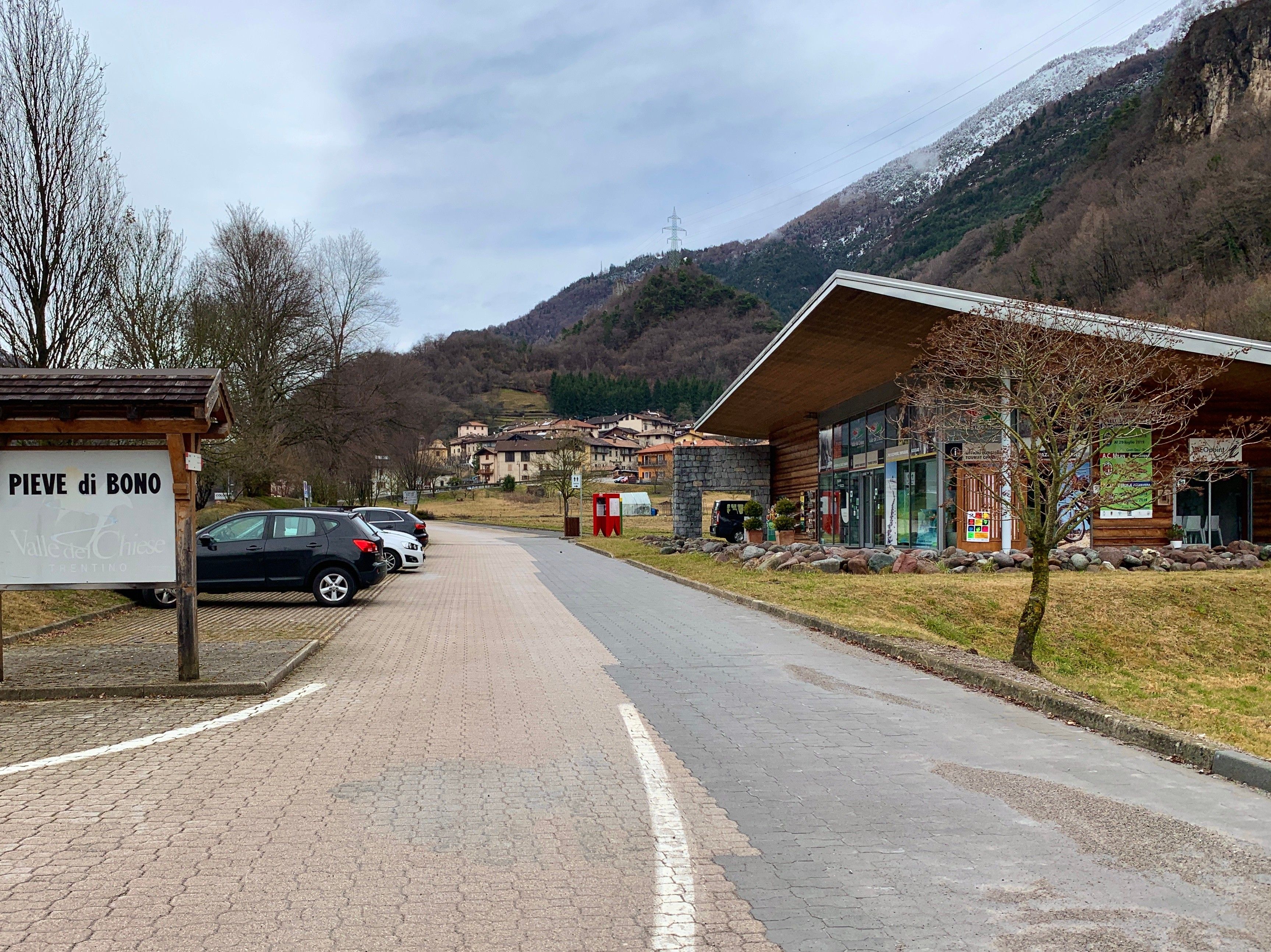 Una strada asfaltata che conduce a un edificio con un cartello che recita 'PIEVE di BONO'.