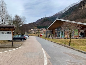 En asfalteret vej fører hen til en bygning med skiltet 'PIEVE di BONO'.