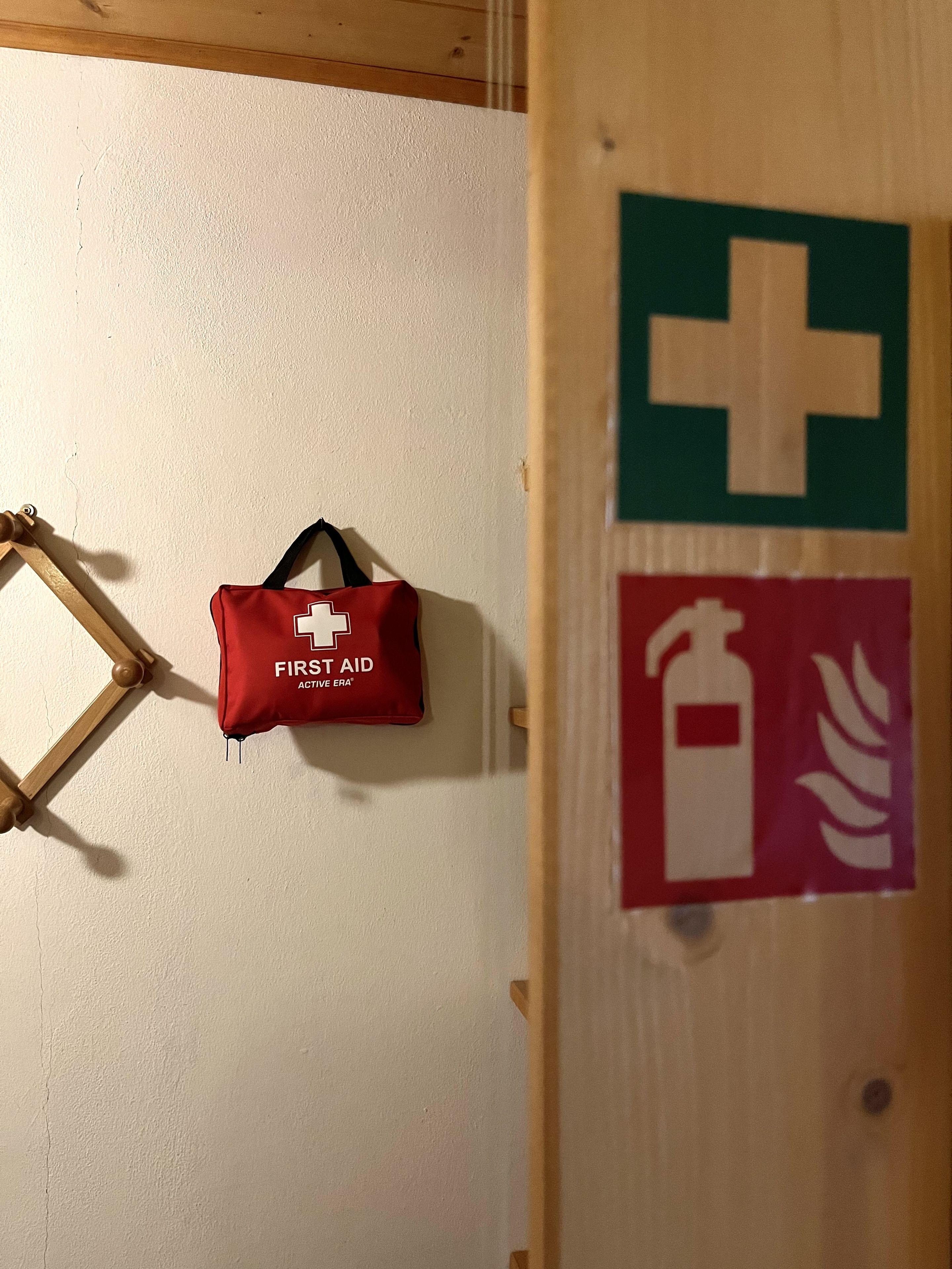 A wall with a first aid bag and emergency exit signs.