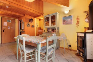 A wooden interior with a dining table, chairs, a cabinet, and a stove. - Casa Aliza – Alpine Duplex with Mountain View, Balcony and Wi-Fi (Creto)