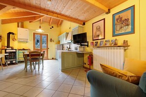 A kitchen with a dining table and chairs, a television, and a fireplace. - Casa Aliza – Alpine Duplex with Mountain View, Balcony and Wi-Fi (Creto)
