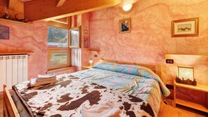 Un dormitorio con cama, mesita de noche, lámpara, ventana y pared decorada con marcos de fotos.