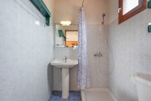 Une salle de bain avec un lavabo sur colonne, une douche et des toilettes.