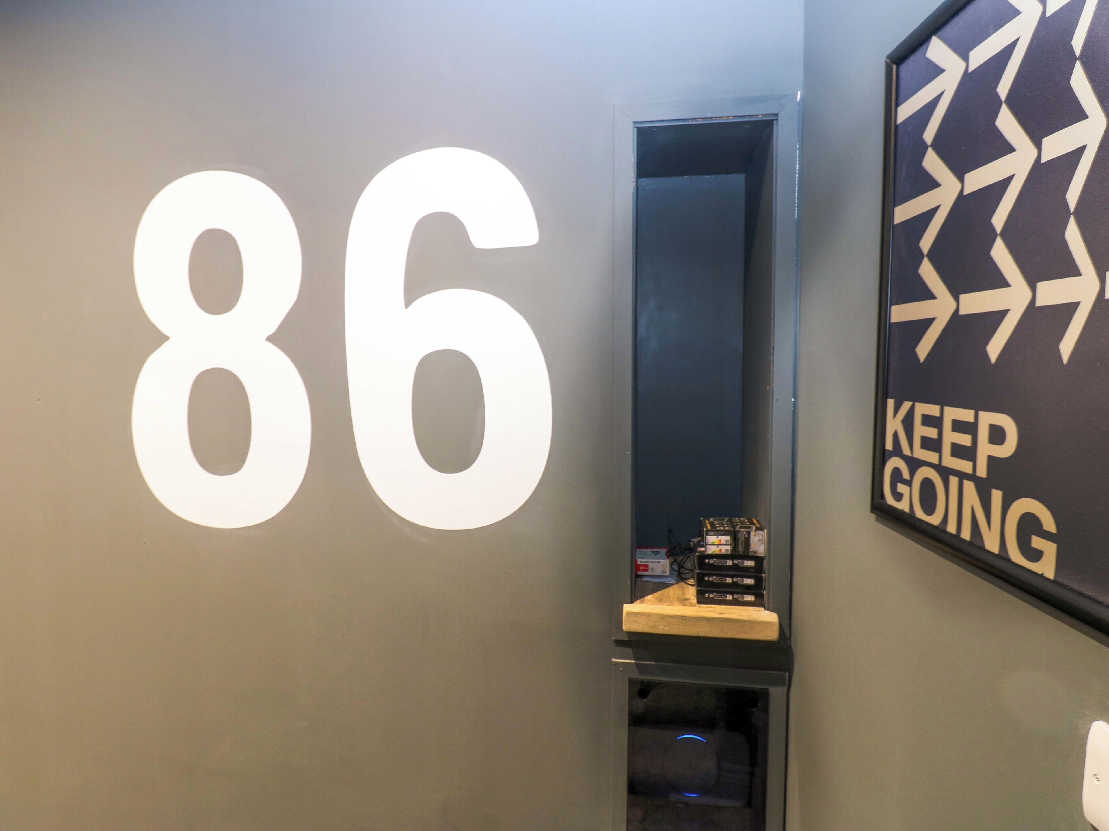 Una pared con el número 86 y un letrero que dice 'KEEP GOING'.