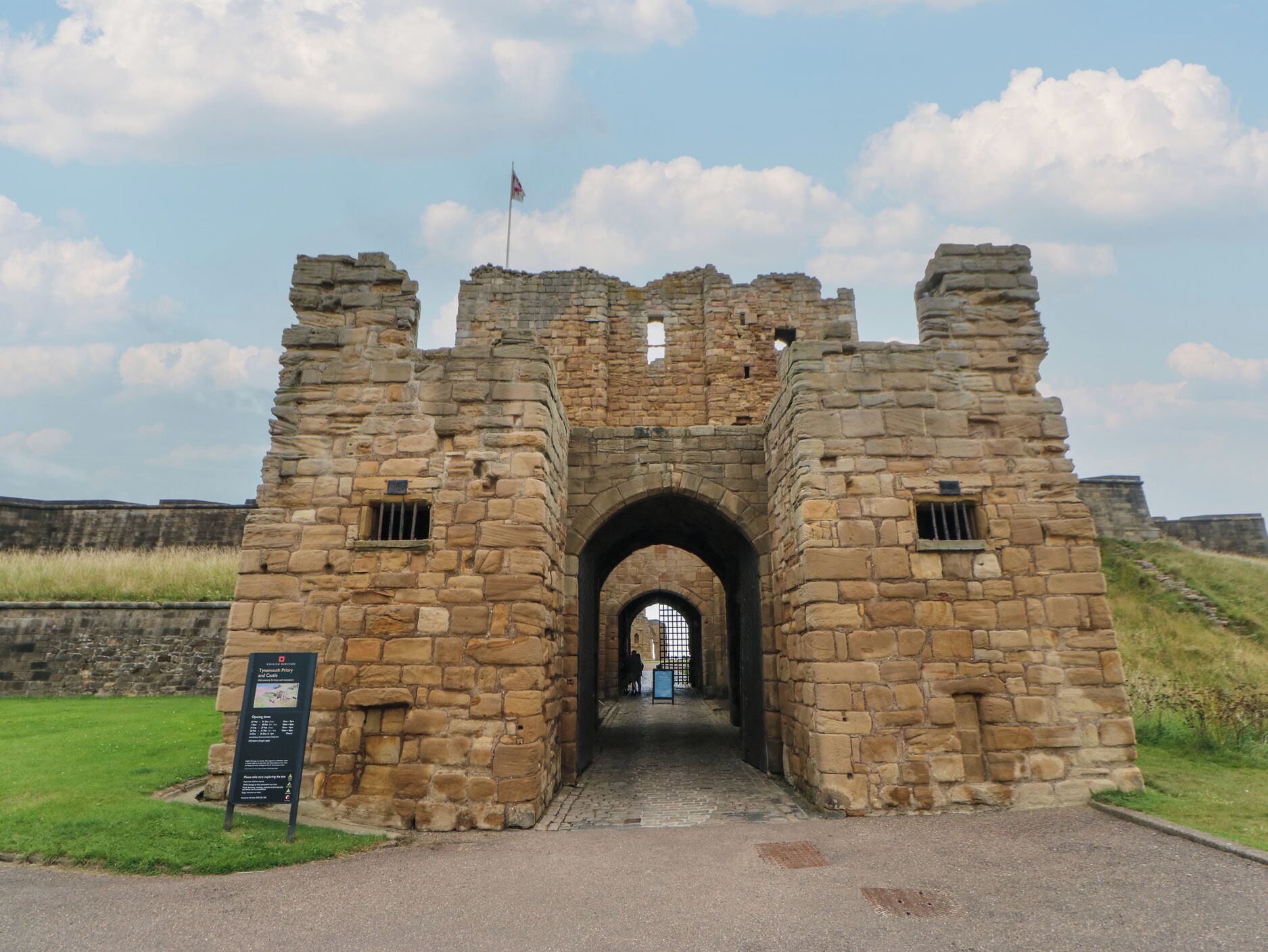 A stone archway leading into a historic building with a flag on top.