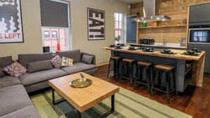 Ein modernes Wohnzimmer mit einer Couch, einem Couchtisch und einer Küchenzeile mit Bar und Hockern.