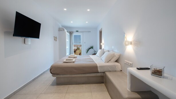 Een moderne hotelkamer met een bed, een flatscreen televisie, een nachtkastje en uitzicht.