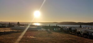 Eine Küstenlandschaft mit Gebäuden, einem klaren Himmel und der Sonne, die über dem Wasser untergeht oder aufgeht.