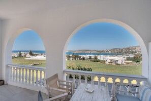Un balcon avec vue sur la mer et un bâtiment visible au loin.