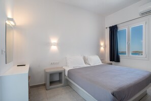 Une chambre à coucher avec un lit, des tables de chevet, un miroir et une fenêtre avec des rideaux.