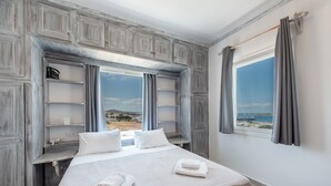 A bedroom with a bed, a window with a view, and built-in shelves. - Diamondbig House Country Home with Jacuzzi and Wi-Fi (Paros)