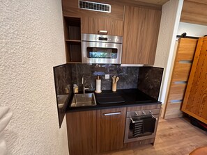 Una cocina compacta con horno integrado, microondas y pileta.