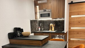 Una cocina moderna con armarios de madera, horno empotrado y encimera negra.
