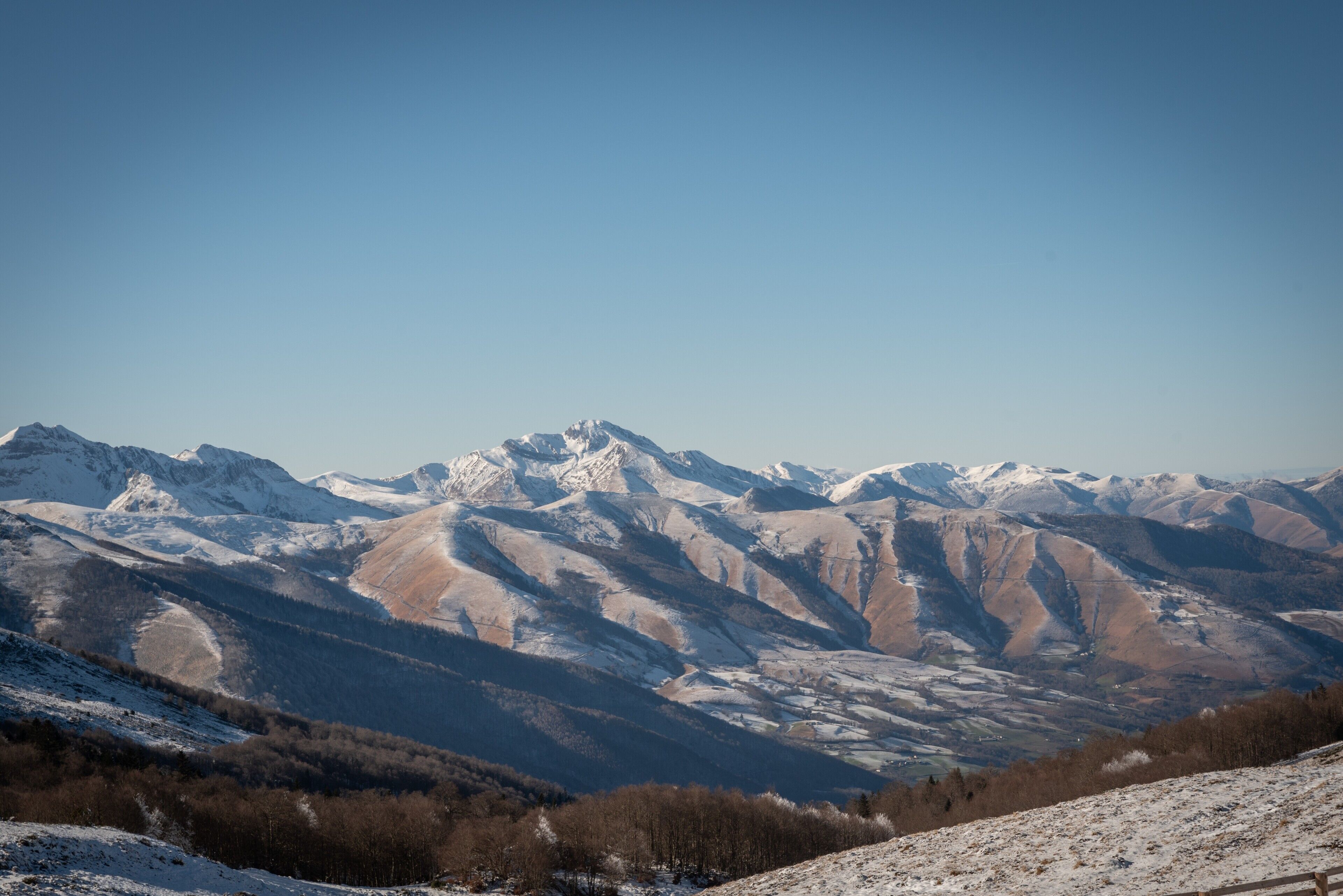 A mountainous landscape with snow-covered peaks and a clear sky.