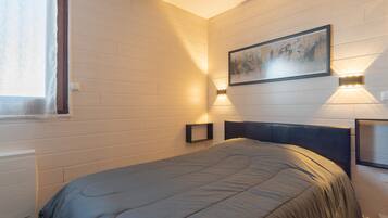 Un dormitorio con cama, ventana e iluminación en la pared.