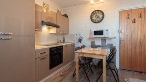 Una cocina compacta con electrodomésticos modernos, una mesa de comedor y una puerta de madera.
