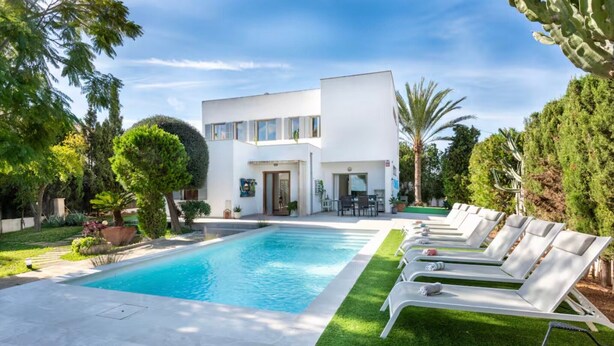 Ein modernes Haus mit Swimmingpool, Liegestühlen und einem gepflegten Garten.