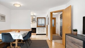 Eine moderne Küche mit weißen Schränken, einer Holz Arbeitsplatte und einem Essbereich mit Tisch und Stühlen.