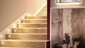 A staircase with wooden steps and a sign indicating a breakfast area. - Hotiday Napoli Lungomare (Naples)