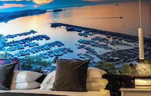 A bed with pillows and a view of a marina with boats. - Hotiday Napoli Lungomare (Naples)
