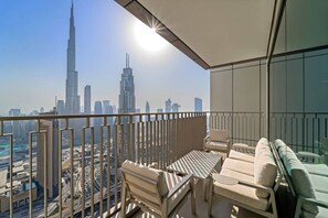 Un balcon avec vue sur la ville, notamment sur le Burj Khalifa, et un espace salon avec une table et des chaises.