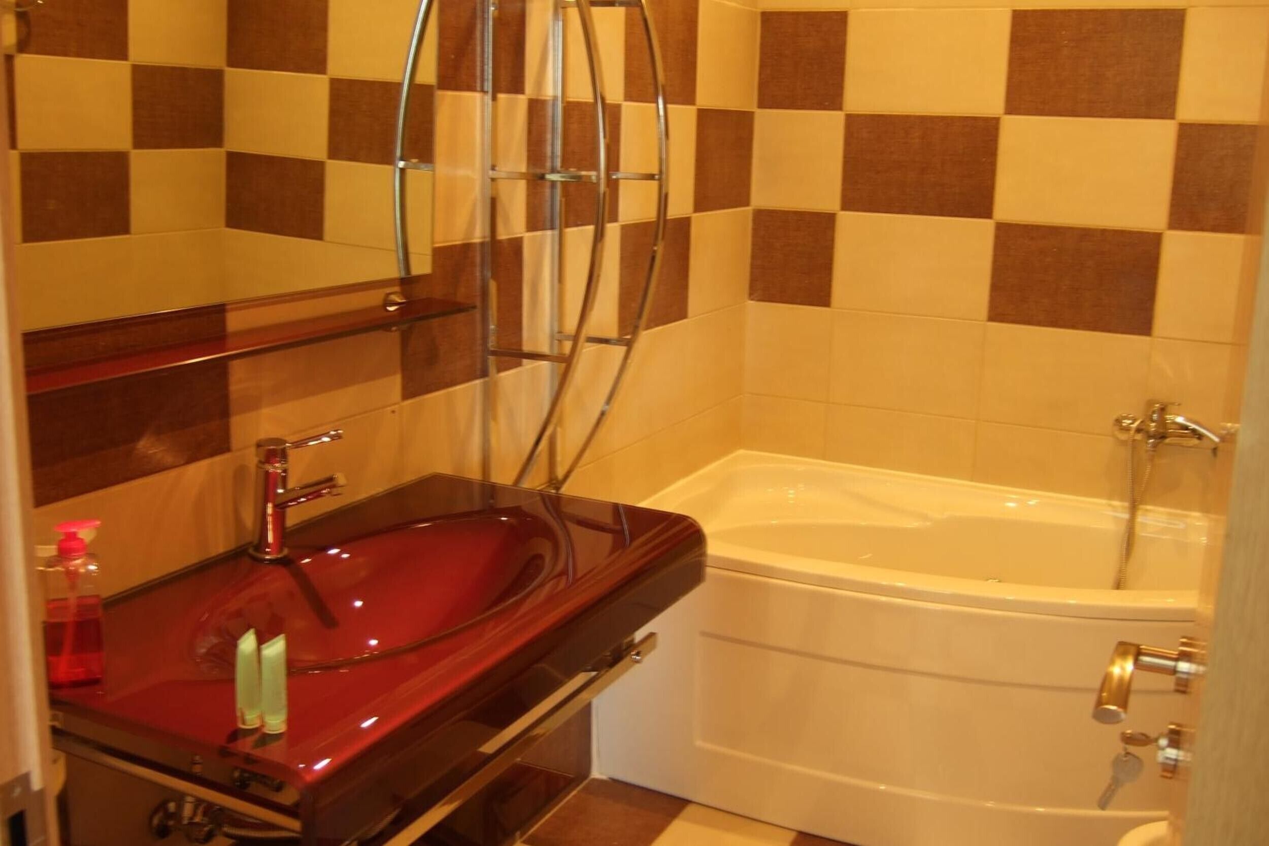 A bathroom with a red sink, a mirror, a shower, and a bathtub.
